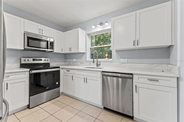 kitchen with light tile patterned flooring, sink, white cabinetry, and stainless steel appliances