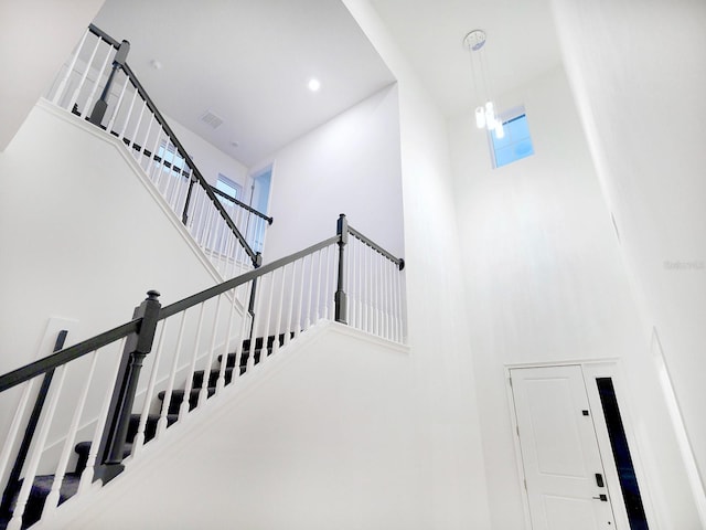 stairway featuring a towering ceiling and an inviting chandelier