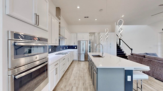 kitchen featuring a center island with sink, sink, white cabinetry, and stainless steel appliances