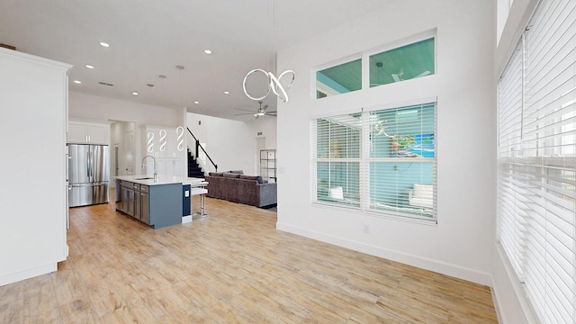 kitchen featuring white cabinetry, sink, stainless steel fridge, a kitchen bar, and a kitchen island with sink