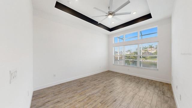 unfurnished room with light hardwood / wood-style flooring, a raised ceiling, and ceiling fan