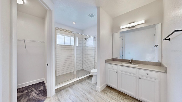 bathroom with toilet, hardwood / wood-style floors, vanity, and walk in shower