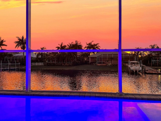 pool at dusk featuring a water view