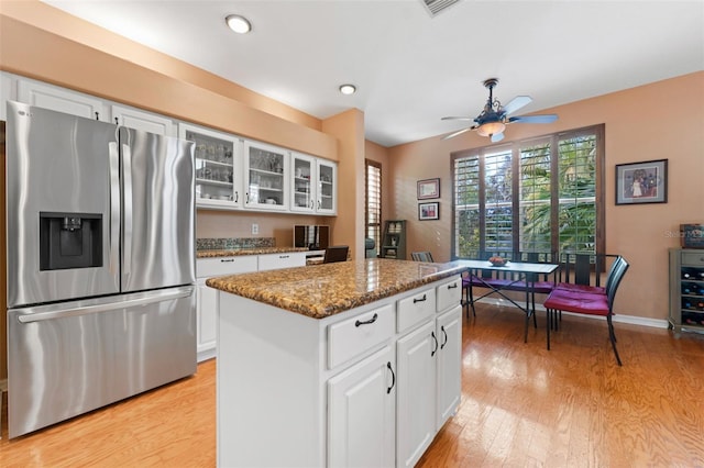 kitchen with a center island, light hardwood / wood-style flooring, stainless steel fridge with ice dispenser, white cabinets, and stone countertops