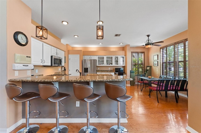 kitchen featuring white cabinetry, pendant lighting, appliances with stainless steel finishes, and kitchen peninsula