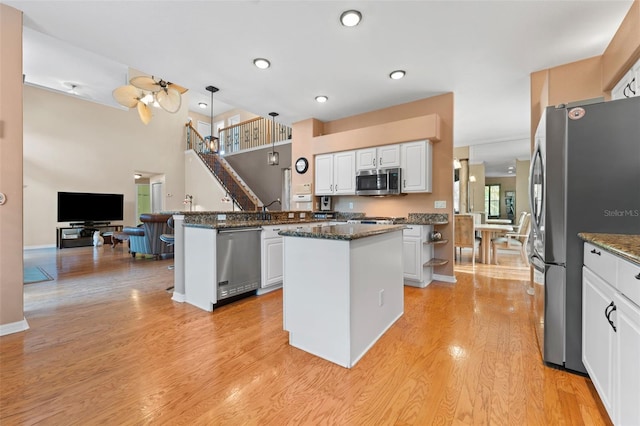 kitchen with appliances with stainless steel finishes, pendant lighting, white cabinetry, and a kitchen island