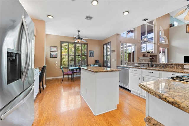 kitchen featuring pendant lighting, white cabinets, appliances with stainless steel finishes, dark stone counters, and sink