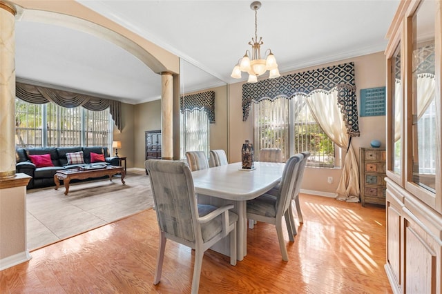 dining room with ornate columns, ornamental molding, light hardwood / wood-style flooring, and an inviting chandelier