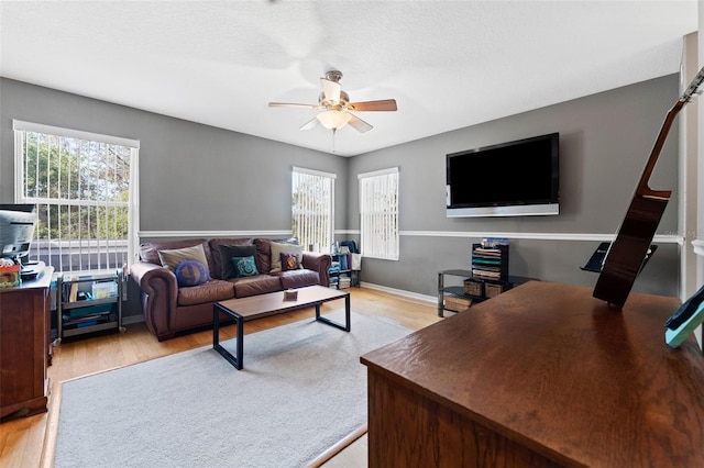 living room with ceiling fan, a textured ceiling, and light hardwood / wood-style floors