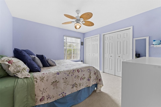 carpeted bedroom featuring ceiling fan and two closets