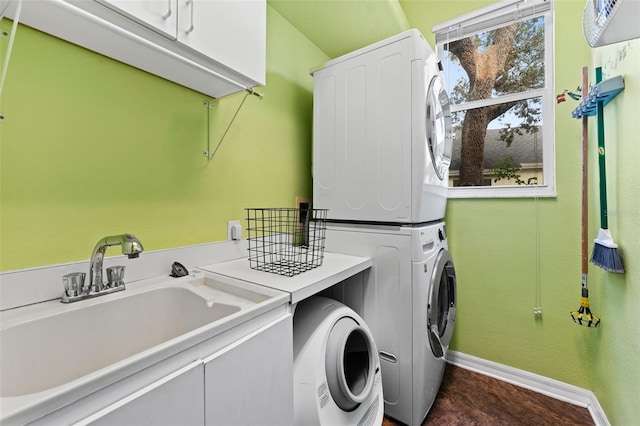 laundry room with stacked washer and dryer, sink, and cabinets