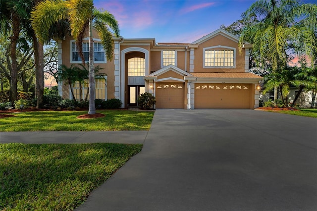 view of front of property with a garage and a lawn