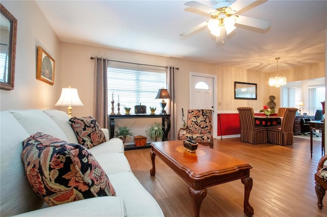 living room featuring light hardwood / wood-style floors and ceiling fan with notable chandelier