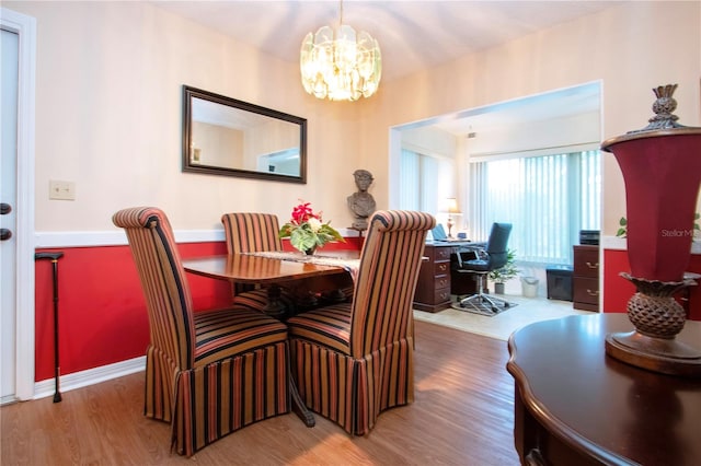 dining area featuring wood-type flooring and an inviting chandelier