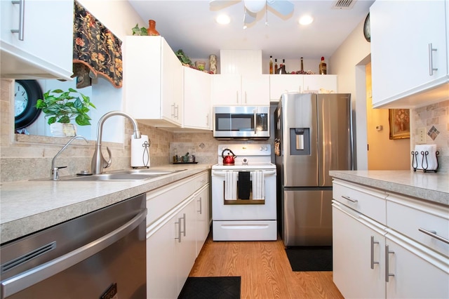 kitchen featuring white cabinetry, sink, appliances with stainless steel finishes, backsplash, and light hardwood / wood-style flooring