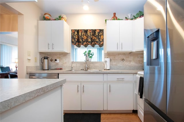 kitchen with white cabinets, appliances with stainless steel finishes, sink, and tasteful backsplash