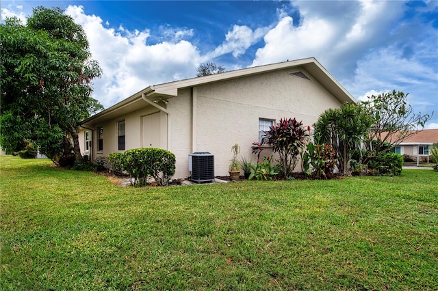 view of side of home with central AC and a yard