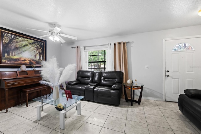 living room featuring a textured ceiling, light tile patterned floors, and ceiling fan