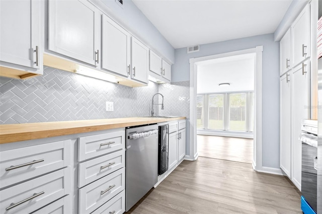 kitchen with butcher block counters, dishwasher, decorative backsplash, white cabinets, and sink