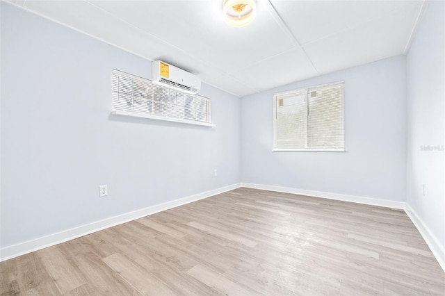 spare room with an AC wall unit and light wood-type flooring