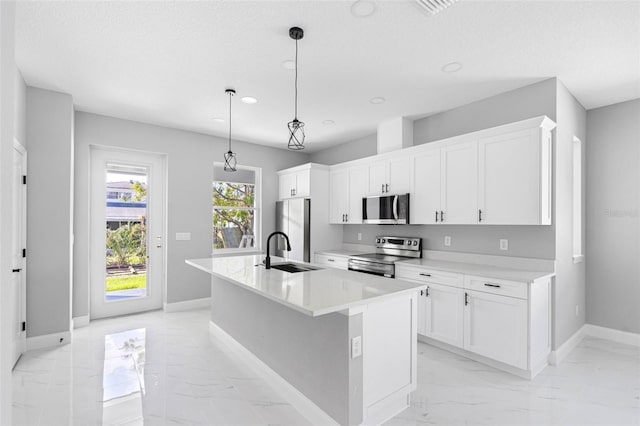 kitchen featuring pendant lighting, stainless steel appliances, a kitchen island with sink, and white cabinets