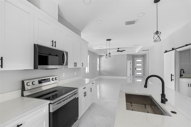 kitchen with sink, appliances with stainless steel finishes, a barn door, and hanging light fixtures