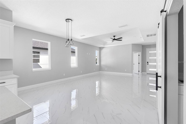 interior space featuring a raised ceiling, a textured ceiling, ceiling fan, and a barn door