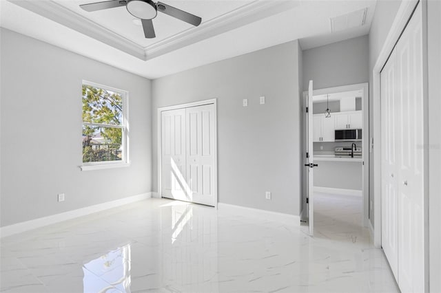 spare room with ceiling fan, crown molding, a tray ceiling, and sink