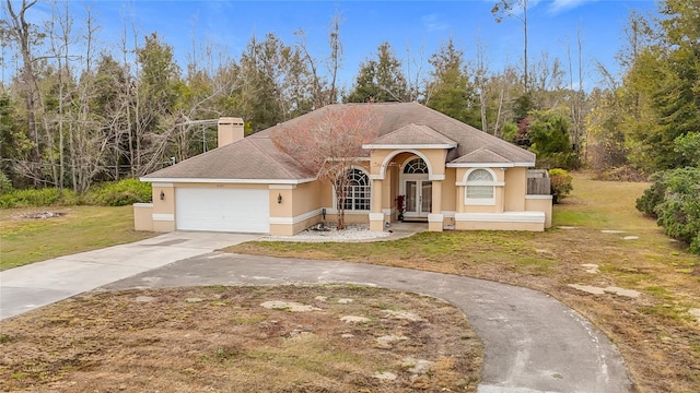 view of front of home with a garage, a front yard, and french doors