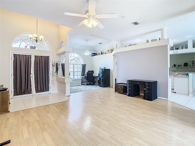 entrance foyer with ceiling fan with notable chandelier and light wood-type flooring