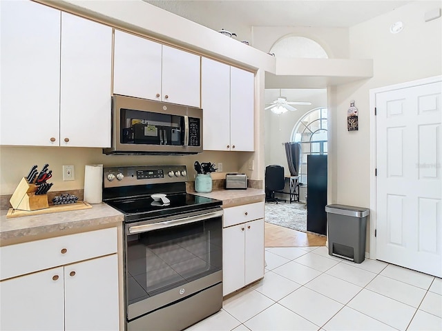 kitchen with light tile patterned floors, ceiling fan, stainless steel appliances, and white cabinets