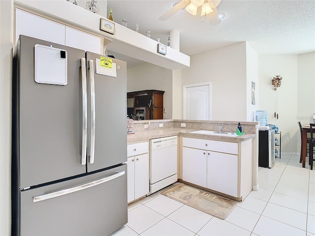 kitchen featuring kitchen peninsula, white dishwasher, white cabinets, and stainless steel fridge