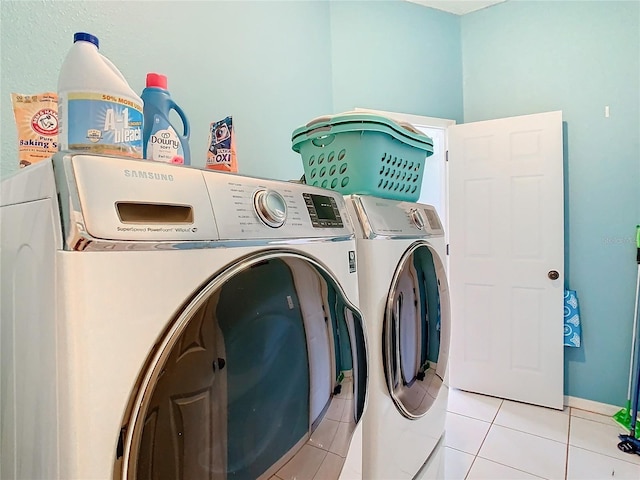 clothes washing area featuring light tile patterned flooring and washer and dryer