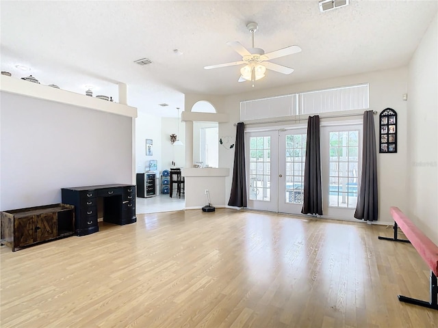 living room featuring ceiling fan, a textured ceiling, hardwood / wood-style floors, and french doors