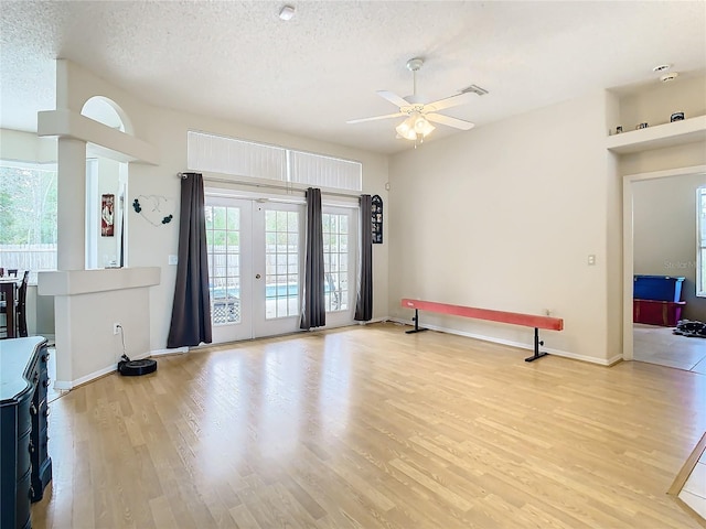 interior space featuring a textured ceiling, ceiling fan, french doors, and light wood-type flooring