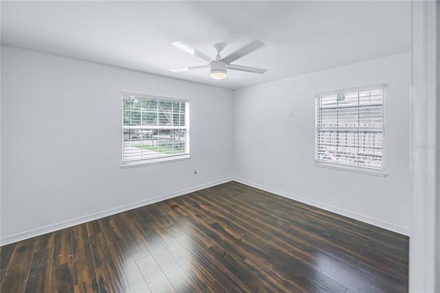 empty room with a wealth of natural light, dark hardwood / wood-style floors, and ceiling fan