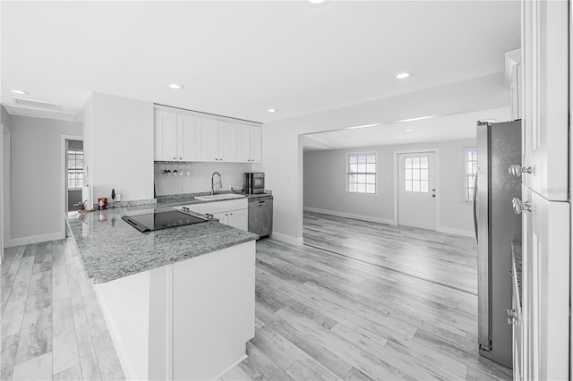 kitchen with sink, appliances with stainless steel finishes, kitchen peninsula, white cabinets, and light wood-type flooring