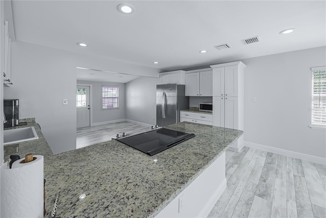 kitchen featuring white cabinetry, kitchen peninsula, light stone counters, and stainless steel appliances