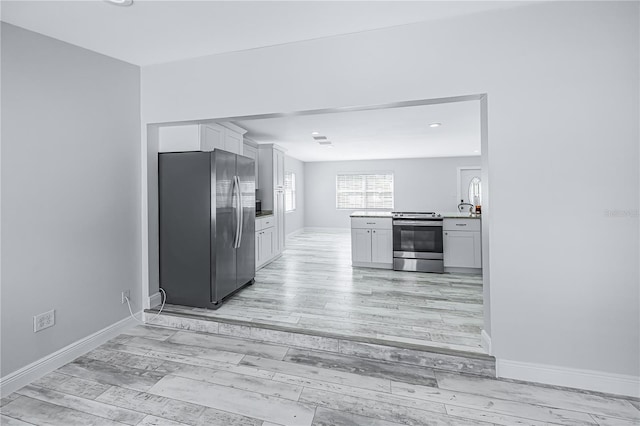 kitchen with white cabinetry, appliances with stainless steel finishes, and light hardwood / wood-style floors