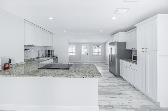 kitchen featuring stainless steel refrigerator, sink, white cabinets, kitchen peninsula, and light hardwood / wood-style flooring