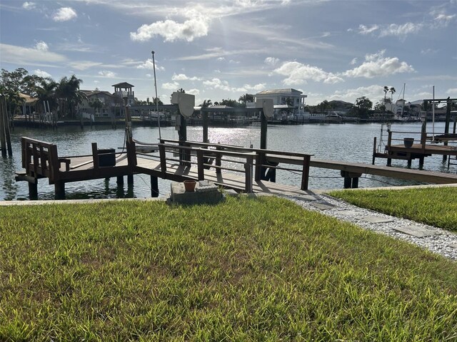 dock area with a lawn and a water view