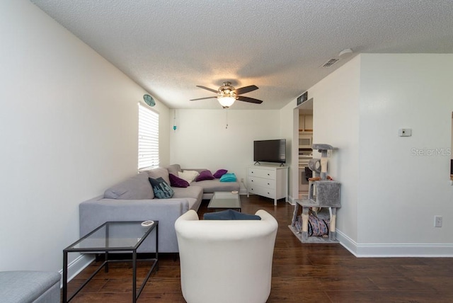 living room featuring a textured ceiling, dark wood-type flooring, and ceiling fan