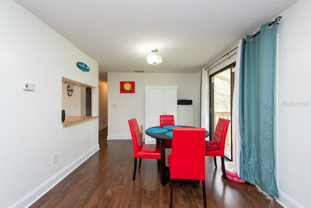 dining room featuring dark wood-type flooring and a textured ceiling