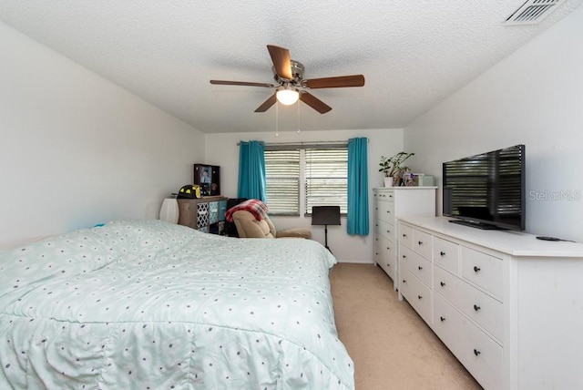 carpeted bedroom with ceiling fan and a textured ceiling