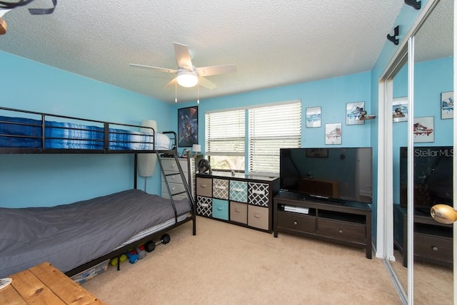 carpeted bedroom with ceiling fan and a textured ceiling