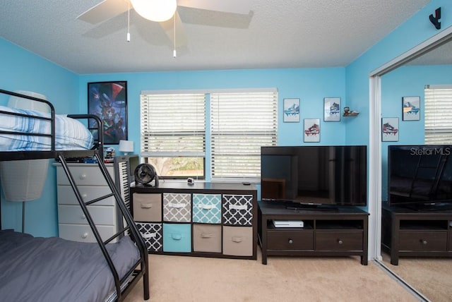 bedroom with a textured ceiling, light colored carpet, and ceiling fan