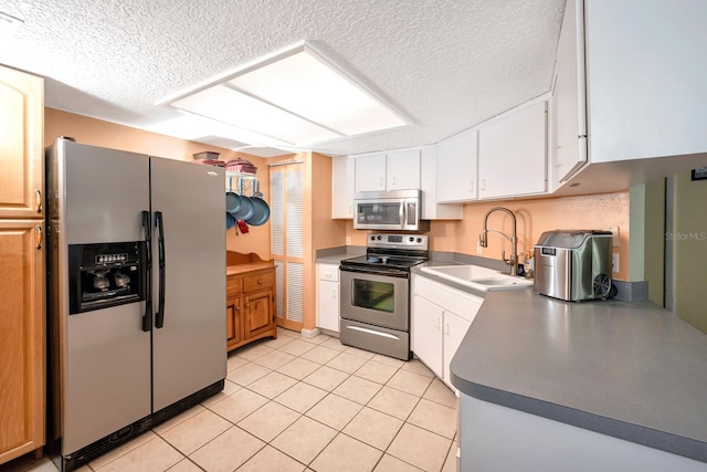 kitchen featuring white cabinets, sink, a textured ceiling, appliances with stainless steel finishes, and light tile patterned flooring