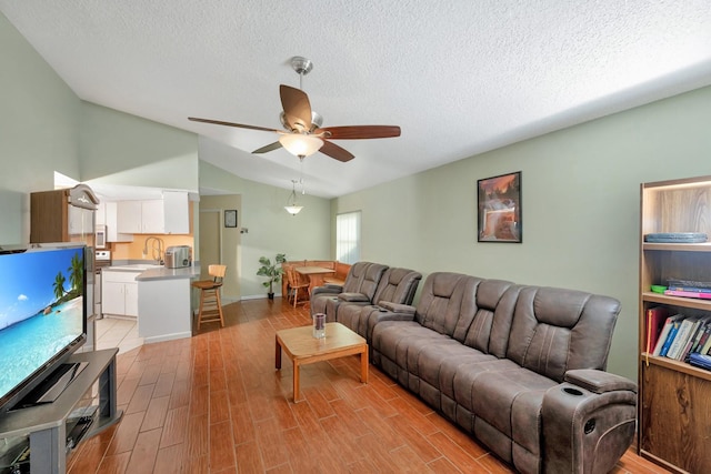 living room featuring ceiling fan, sink, a textured ceiling, and light hardwood / wood-style flooring