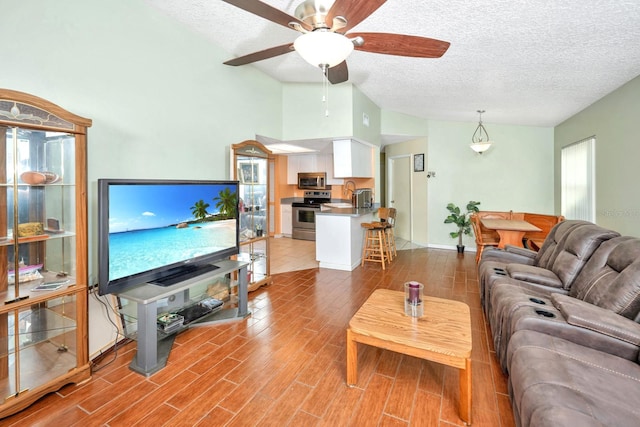 living room featuring a textured ceiling, ceiling fan, sink, light hardwood / wood-style flooring, and lofted ceiling