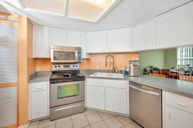 kitchen with sink, white cabinetry, stainless steel appliances, and light tile patterned floors